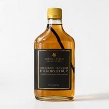 Load image into Gallery viewer, Bottle of Arbor and Field Black Label Bourbon-Infused Shagbark Hickory Syrup with black and gold foil label. A piece if bourbon-infused shagbark hickory bark can be seen inside of the bottle. Clean white background, premium look and feel.