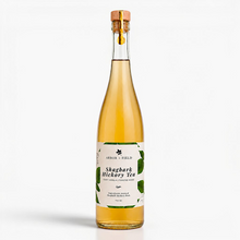 Load image into Gallery viewer, Bottle of Arbor and Field shagbark hickory tea with a wooden cork and green and white label. Modern clear glass wine bottle with amber colored tea inside. Clean white background, premium look and feel.