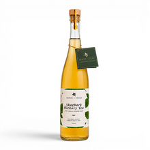 Load image into Gallery viewer, Bottle of Arbor and Field shagbark hickory tea with a wooden cork, green and white label and a green gift tag hanging from the neck by a gold string. Modern clear glass wine bottle with amber colored tea inside. Clean white background, premium look and feel.