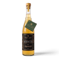 Bottle of bourbon-infused hickory tea with a cork lid on a white background