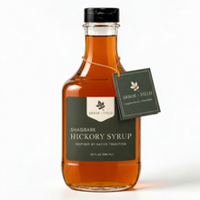Load image into Gallery viewer, Shagbark Hickory Syrup 32 oz decanter bottle with green and cream Arbor and Field Label on the front, a gold wax dipped cap and dark green gift tag hanging around the neck of the bottle  from a gold string. Clean white background, premium look and feel. 
